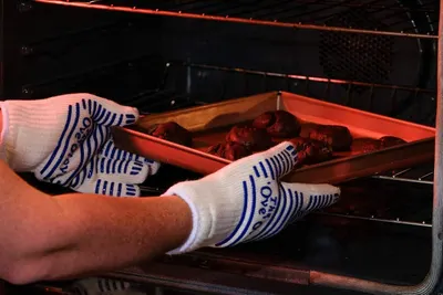 Demonstrates the heat-resistant capability of the gloves by showing them safely handling a hot tray from the oven, reassuring customers they can protect their hands from burns.
