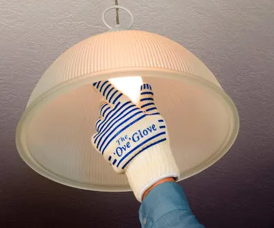 Demonstrates that the glove can safely handle hot objects like light bulbs without burning the user, reassuring shoppers of its heat protection capability.