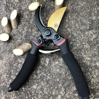 Demonstrates the product in a real-world gardening or pruning scenario, showing the pruning shears cutting through small branches to help shoppers visualize practical use.