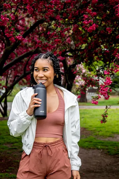 Demonstrates the product being used in a real-world outdoor setting to help shoppers visualize the water bottle as part of an active, healthy lifestyle.