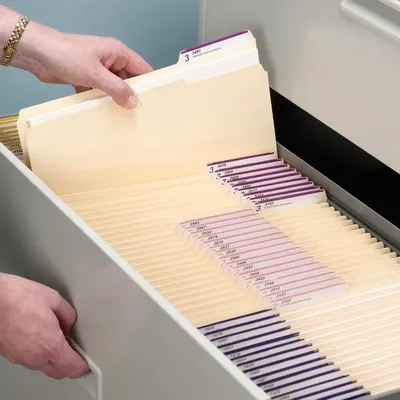 Demonstrates the product in a real-world office setting, showing how the filing system organizes documents in a drawer with hands interacting naturally with the folders.