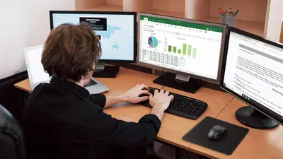 Demonstrates the product in a real-world professional office setting, showing how it enables a productive multi-screen workflow for business or data analysis tasks.
