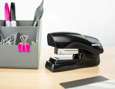 Shows the stapler in a real-world office setting to help shoppers visualize how it fits naturally on a desk alongside other office supplies.