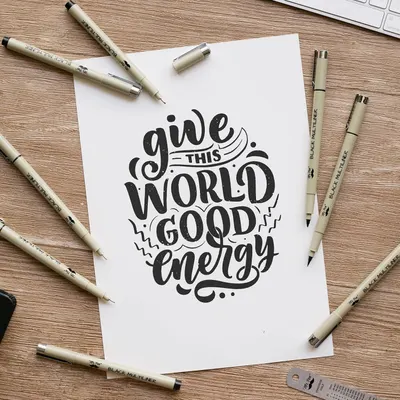 Demonstrates the product (pens/markers) in a real-world creative setting to show how they can be used for hand lettering and artistic projects.