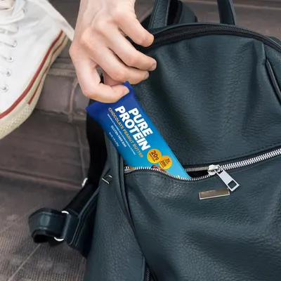 Demonstrates that the protein bar is compact and portable, fitting easily into a bag for on-the-go nutrition and convenience.