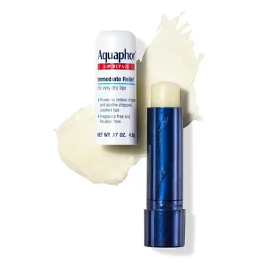 Displays the Aquaphor Lip Repair product in its packaging alongside a blue lipstick-style applicator and a cream texture swatch to show the product format and consistency in a clean, catalog-style…