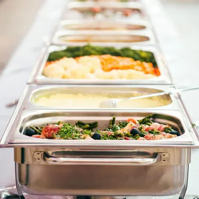 Demonstrates the product in a real-world catering or food service setting, showing how the chafing dish/food warmer holds and presents multiple dishes attractively.
