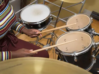 Shows the drum set being played in a real-world context to help shoppers visualize the product in action and understand its practical application.
