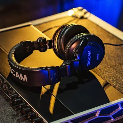 Showcases the headphones in a real-world professional audio/gaming environment to help shoppers visualize the product in use and establish its premium positioning.