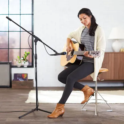 Shows the product (microphone stand) being used in a realistic home or studio environment to help shoppers visualize how it fits into their own space and usage scenarios.
