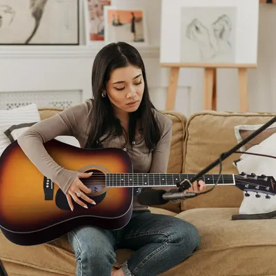 Demonstrates the product being used in a real-world home setting to help shoppers visualize the guitar in their own lifestyle and creative practice.