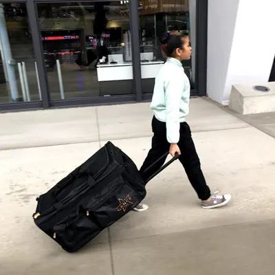 Demonstrates the product in a real-world travel scenario, showing a young person easily pulling the rolling bag through an urban environment to communicate its practical portability and…