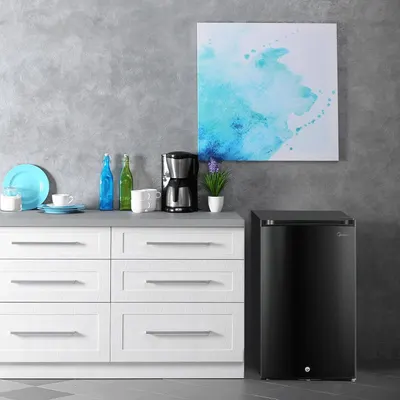 Demonstrates how the compact refrigerator fits naturally into a modern kitchen or living space, helping shoppers visualize the product in their own home environment.