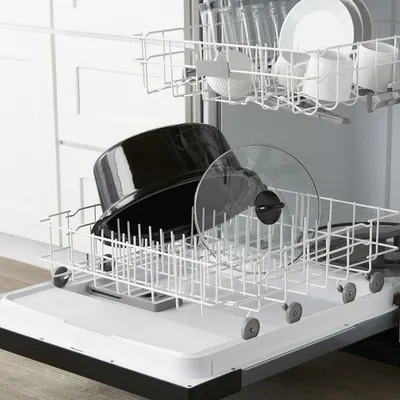Demonstrates the product in a real-world kitchen context, showing pots and pans loaded in a dishwasher to communicate ease of cleaning and dishwasher compatibility.