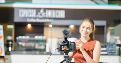 Demonstrates the product's use case for video content creation and vlogging, showing it in a real-world café setting to communicate its suitability for creators. Shows the camera setup being used in…