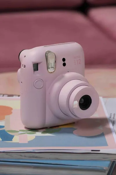 Shows the Instax camera in a lifestyle setting with printed photos to help shoppers visualize the product in everyday use and create an emotional connection.