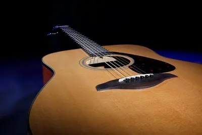 Showcases the acoustic guitar in an artistic, professional setting to emphasize its craftsmanship and appeal to musicians seeking quality instruments.