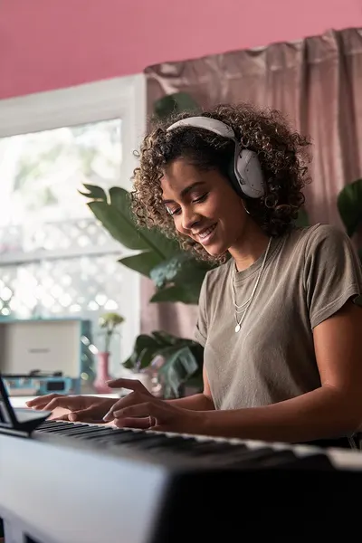 Shows the product (headphones) being used in a real-world home setting to help shoppers visualize how they would use it in their daily life for work or leisure.