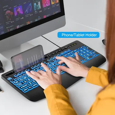 Demonstrates the keyboard's built-in phone/tablet holder feature, showing how users can conveniently position their mobile device while typing for improved multitasking and ergonomics.