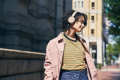Demonstrates the product (headphones) being used naturally in an everyday outdoor setting to help shoppers visualize the product in their own life.
