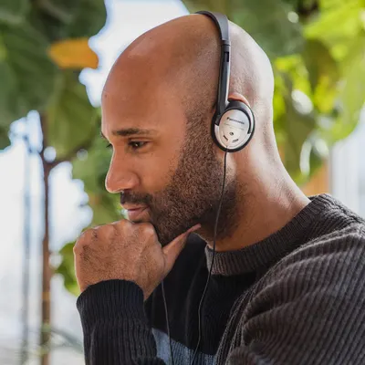 Shows the product being used in a natural outdoor setting to help shoppers visualize themselves using the headphones in everyday life.