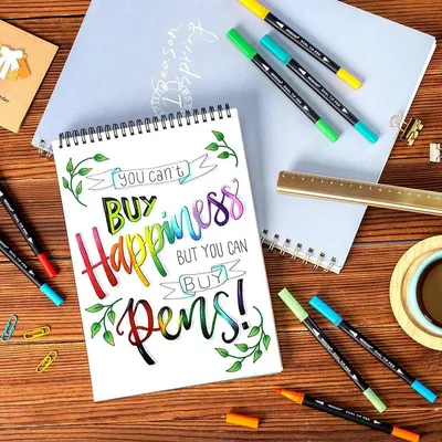 Demonstrates the product (dual tip pens) in a real-world creative context, showing the pens being used for hand lettering and artistic work to help shoppers visualize how they might use the product…