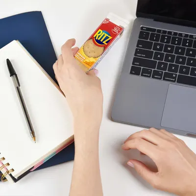 Demonstrates the product being used in a real-world office or work-from-home setting, showing it as a convenient snack option during work hours.