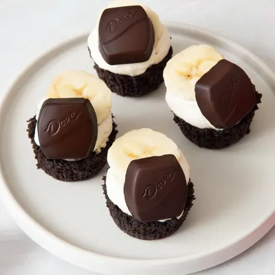 Displays the product in a clean, catalog-style presentation showing the chocolate-topped desserts with banana slices on a white plate, allowing shoppers to see the product clearly without…