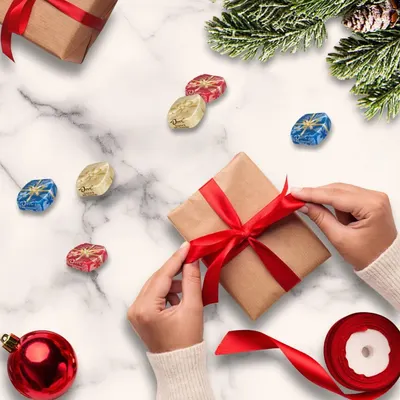 Positions the product as a perfect gift for the holiday season, creating emotional appeal through festive imagery including gift wrapping, ornaments, and evergreen branches. Shows the product in a…