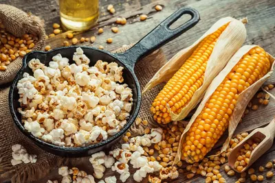 Demonstrates the product transformation visually by showing raw corn kernels alongside the finished popcorn product, proving the natural origin and end result.