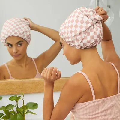 Demonstrates the product in a real-world bathroom setting to help shoppers visualize using the hair towel wrap as part of their daily self-care routine.