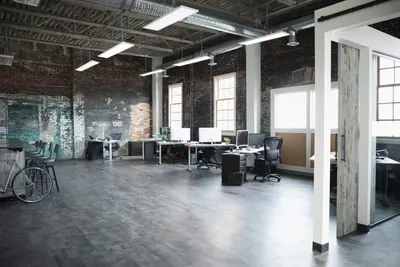 Showcases the product in a real-world office setting with exposed brick and industrial design to help shoppers visualize how it fits into modern workspace environments.