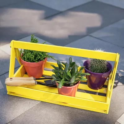 Demonstrates the product in a real-world outdoor setting with plants and gardening tools to show how it can be used for organizing and displaying small potted plants.