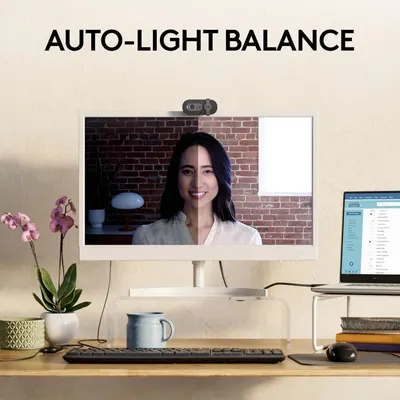 Demonstrates the webcam's automatic light balancing feature by showing a side-by-side comparison of the same person in dark vs. well-lit conditions, proving the product's ability to optimize video…