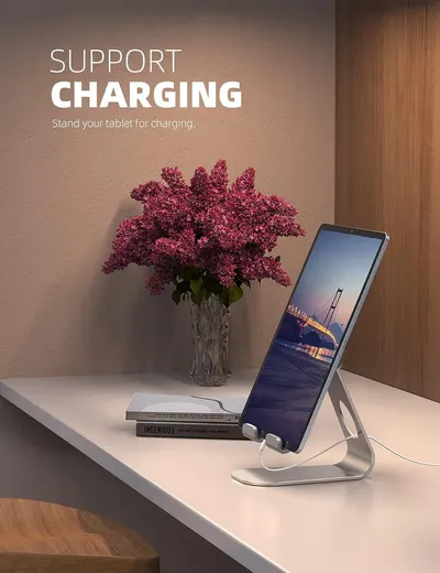 Demonstrates that the tablet stand can hold and support a tablet while charging, showing a practical use case in a home or office environment. Shows the product in a real-world lifestyle context on…