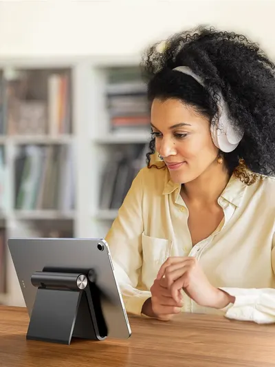 Demonstrates the product (tablet stand) being used in a real-world home office setting to help shoppers visualize how it fits into their daily work routine.