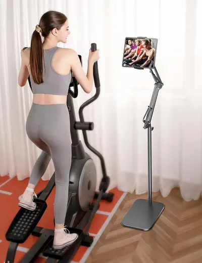 Demonstrates the product in a real-world home fitness setting, showing how the tablet stand enables hands-free viewing during exercise workouts.