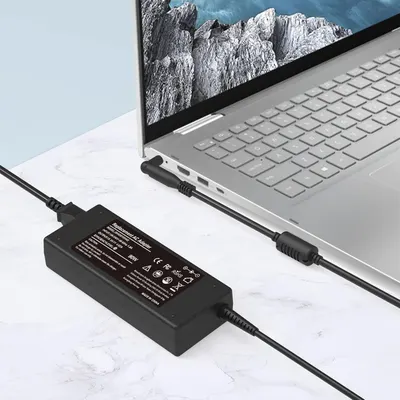 Demonstrates the product in a real-world setting with a laptop to show how the charger/adapter is used in everyday computing scenarios.