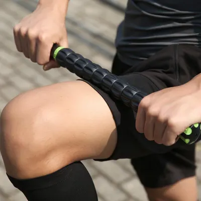 Demonstrates the product in a real-world fitness context, showing how the massage roller is used on the leg to communicate its practical application for muscle recovery and post-workout care.