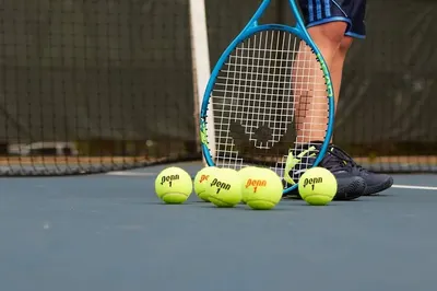 Shows the product in a real-world tennis environment to help shoppers visualize the tennis balls and racket in actual use on the court.