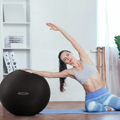Demonstrates the product in a real-world home fitness setting to help shoppers visualize using the exercise ball in their own space.