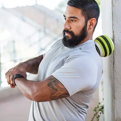 Demonstrates the product being used in a real-world outdoor setting to help shoppers visualize how the massage ball fits into an active lifestyle and recovery routine.