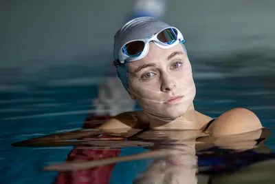 Shows the swim goggles and cap being used in a real swimming pool environment to help shoppers visualize the product in action.
