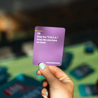 Shows the product (a party/game card) being used in a real-world social setting to demonstrate its entertainment value and how it fits into gameplay.