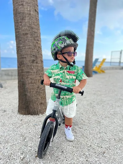 Demonstrates the product in a real-world outdoor environment to help shoppers visualize the bike being used by a child in an active, lifestyle context.