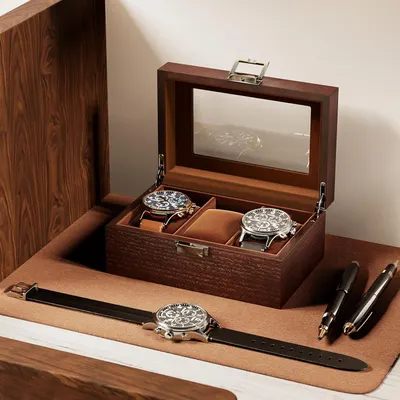 Shows the complete package the customer receives, including a premium wooden display case with glass top, three watches with different straps, and bonus pens, emphasizing the value and completeness…