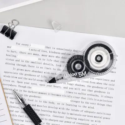 Displays the correction tape product alongside office accessories in a clean, catalog-style presentation to show the product clearly without distractions.