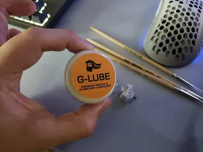 Shows the customer what items are included with the purchase: the G-LUBE lubricant container and two drumsticks, demonstrating this is a complete kit for drummers.