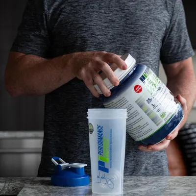 Shows the customer everything included in the purchase: the supplement powder container, a shaker bottle with lid, and the product packaging, demonstrating the complete value of the bundle.