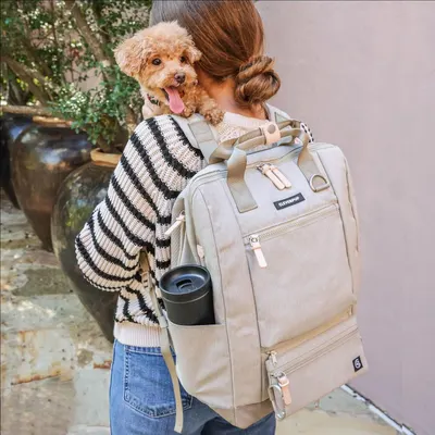 Shows the backpack in a real-world lifestyle context with a dog, demonstrating its use as a pet carrier or travel bag for pet owners.